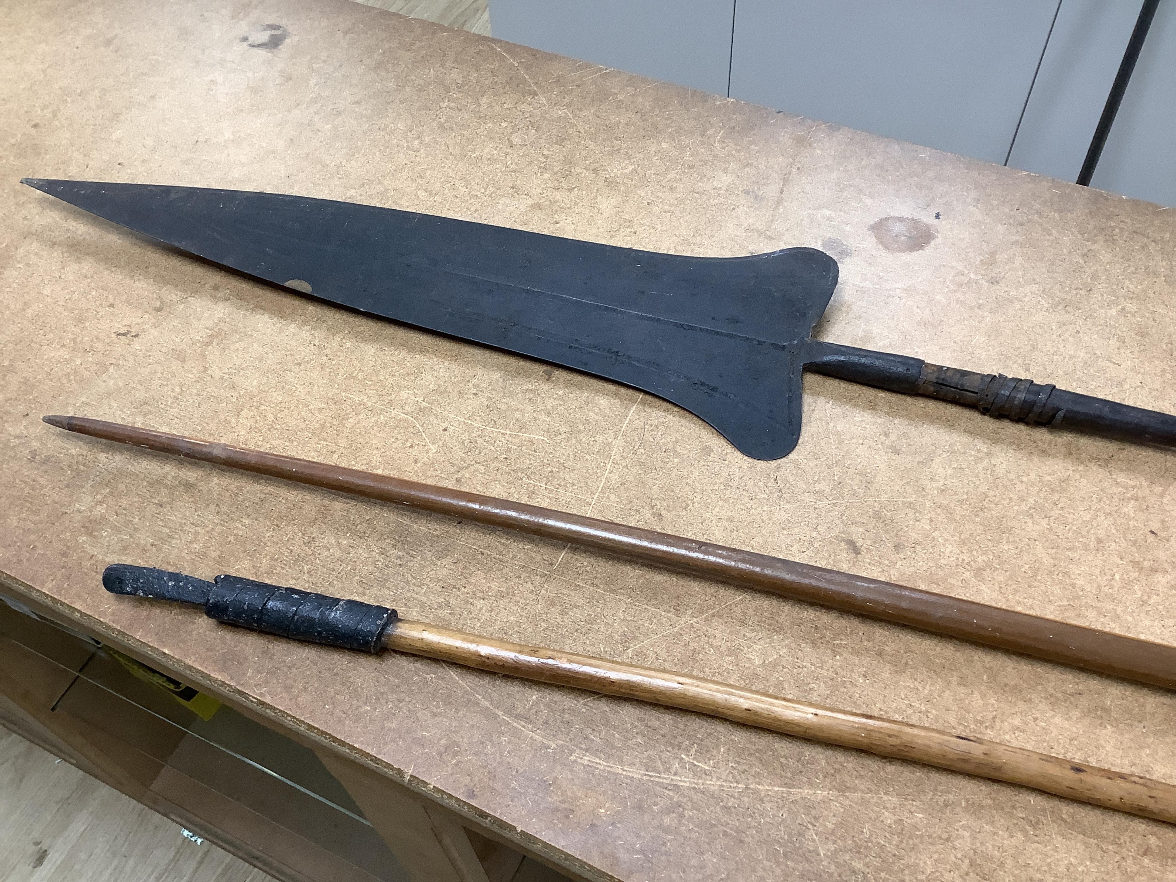 A collection of tribal spears, a fish hook, a cased snooker cue, etc.